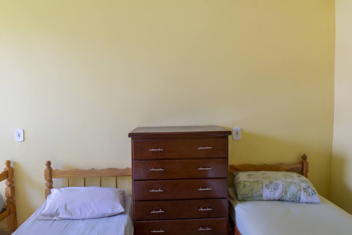 A bedroom with a wooden dresser, a bed with a floral bedspread, and a wooden headboard.