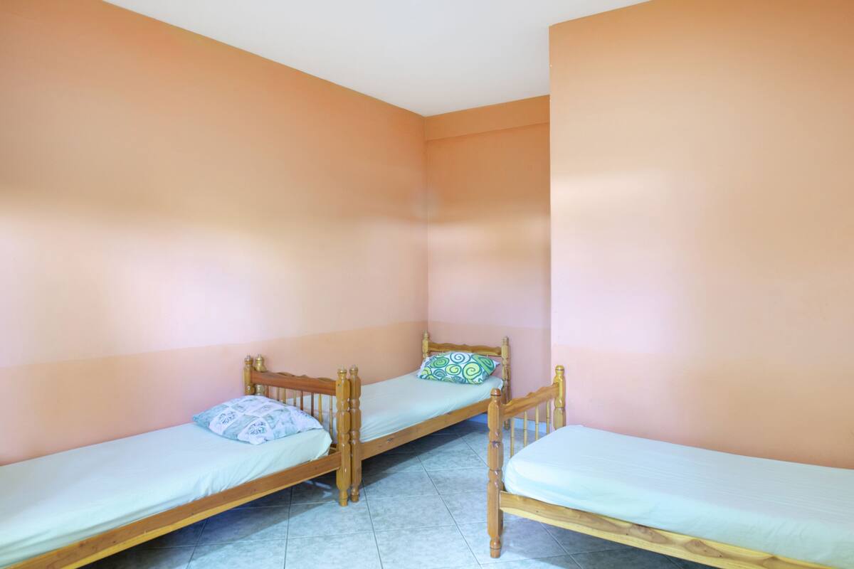 A small, single-room with two wooden bunk beds and a single bed.