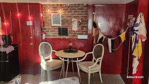 A room with a brick wall, a round table with two chairs, a fire extinguisher, and a sign that reads "BISDENGEN GUEST HOUSE". - Beach, marina, restaurants! 1 bedroom, living room, bath with private entrance! (Wareham)