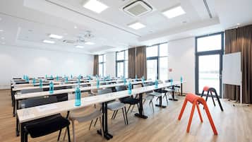 A conference room with rows of tables, chairs, and water bottles.