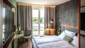 Een hotelkamer met een bed, een bureau met stoel, een televisie en uitzicht op de omgeving.