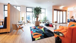 Een moderne zithoek met meubels, een grote plant en een kleurrijk vloerkleed.