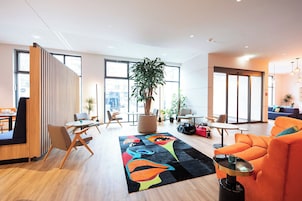 Un'area lounge moderna con posti a sedere, una pianta grande e un tappeto colorato.