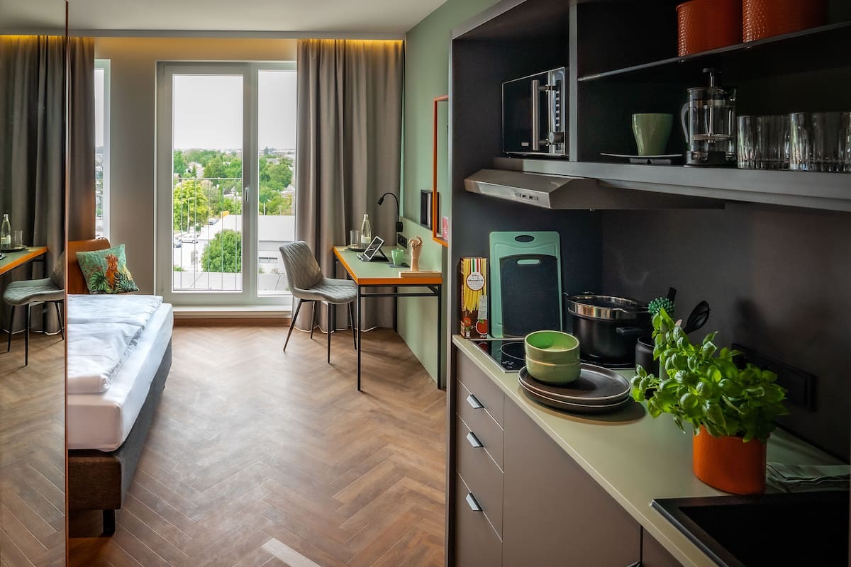 Een moderne hotelkamer met een bed, bureau en kitchenette.