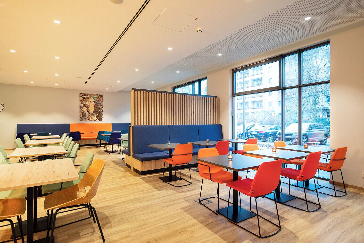 Un área de comedor moderna con asientos tipo cabina y mesas, ventanas amplias y vista a la calle.