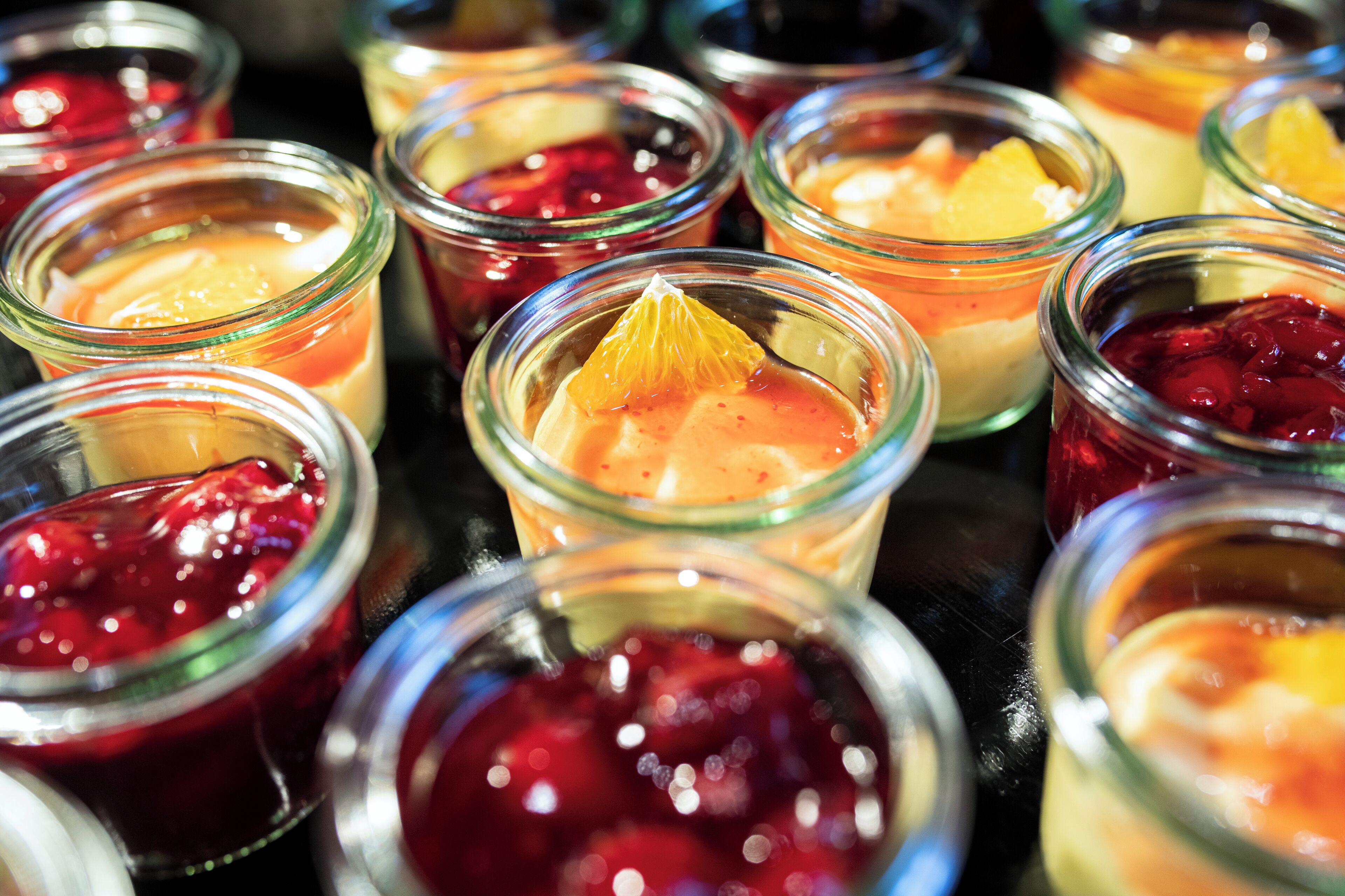 A variety of desserts in small glass jars, each with a different topping.