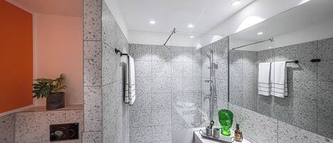 A modern bathroom with a large mirror, a shower, and a sink.