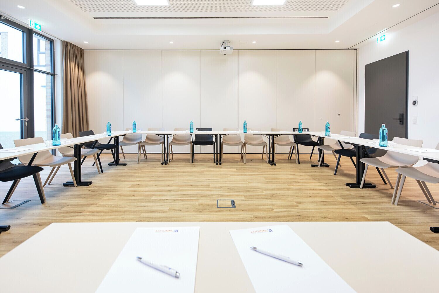 A conference room with a long table, chairs, and a projector screen.