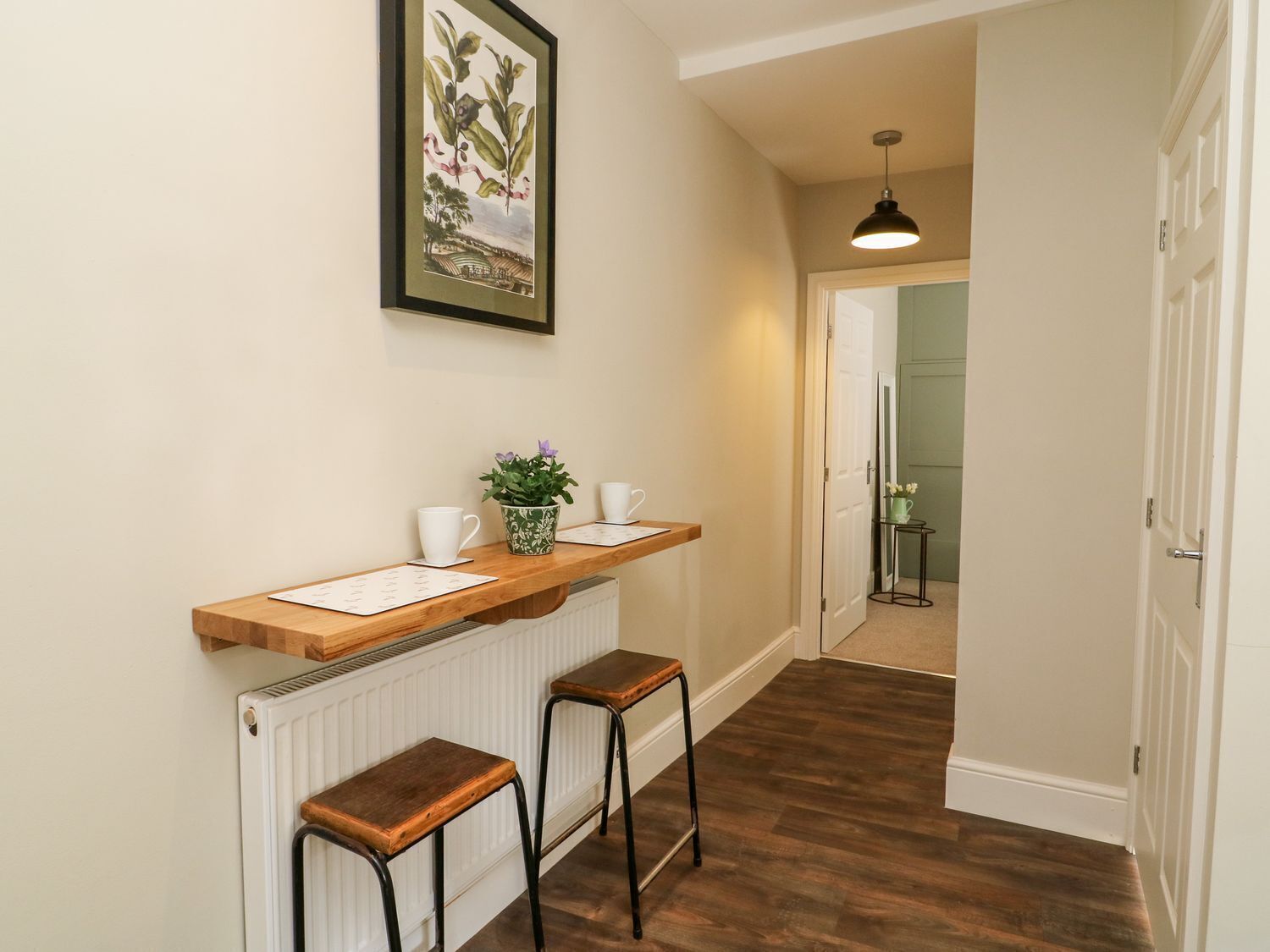 A hallway with a wooden bench, a radiator, and a framed botanical illustration on the wall.