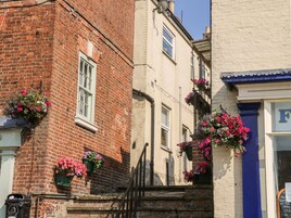 A building with brick and plaster walls, a window, and flower boxes.