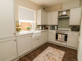 A kitchen with white cabinets, a microwave, a stove, and a window with a view of a brick wall.