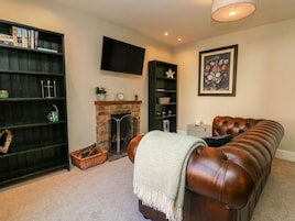 A cozy living room with a fireplace, a television, a bookshelf, and a leather sofa.