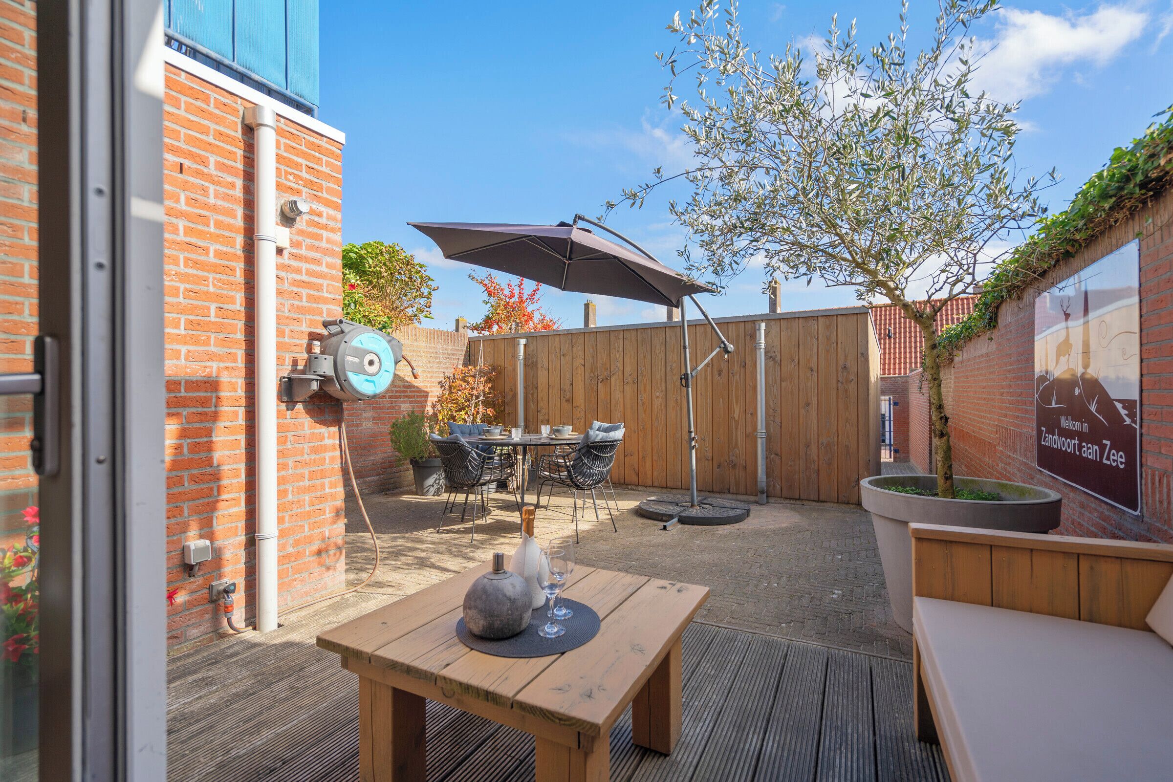 An outdoor patio with a wooden table, chairs, and a large umbrella.