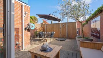 An outdoor patio with a wooden table, chairs, and a large umbrella.