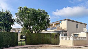 A residential property with a paved driveway, a neatly trimmed hedge, and a large tree providing shade. - Elegant terraced house in a fantastic south position in Els Poblets (Denia)