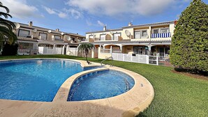 A residential area with a swimming pool, multiple houses, and a well-maintained lawn. - Elegant terraced house in a fantastic south position in Els Poblets (Denia)