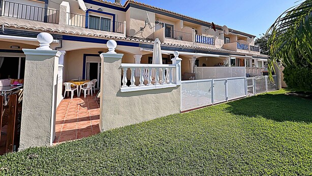 A two-story building with a balcony, a covered patio, and a well-maintained lawn. - Elegant terraced house in a fantastic south position in Els Poblets (Denia)