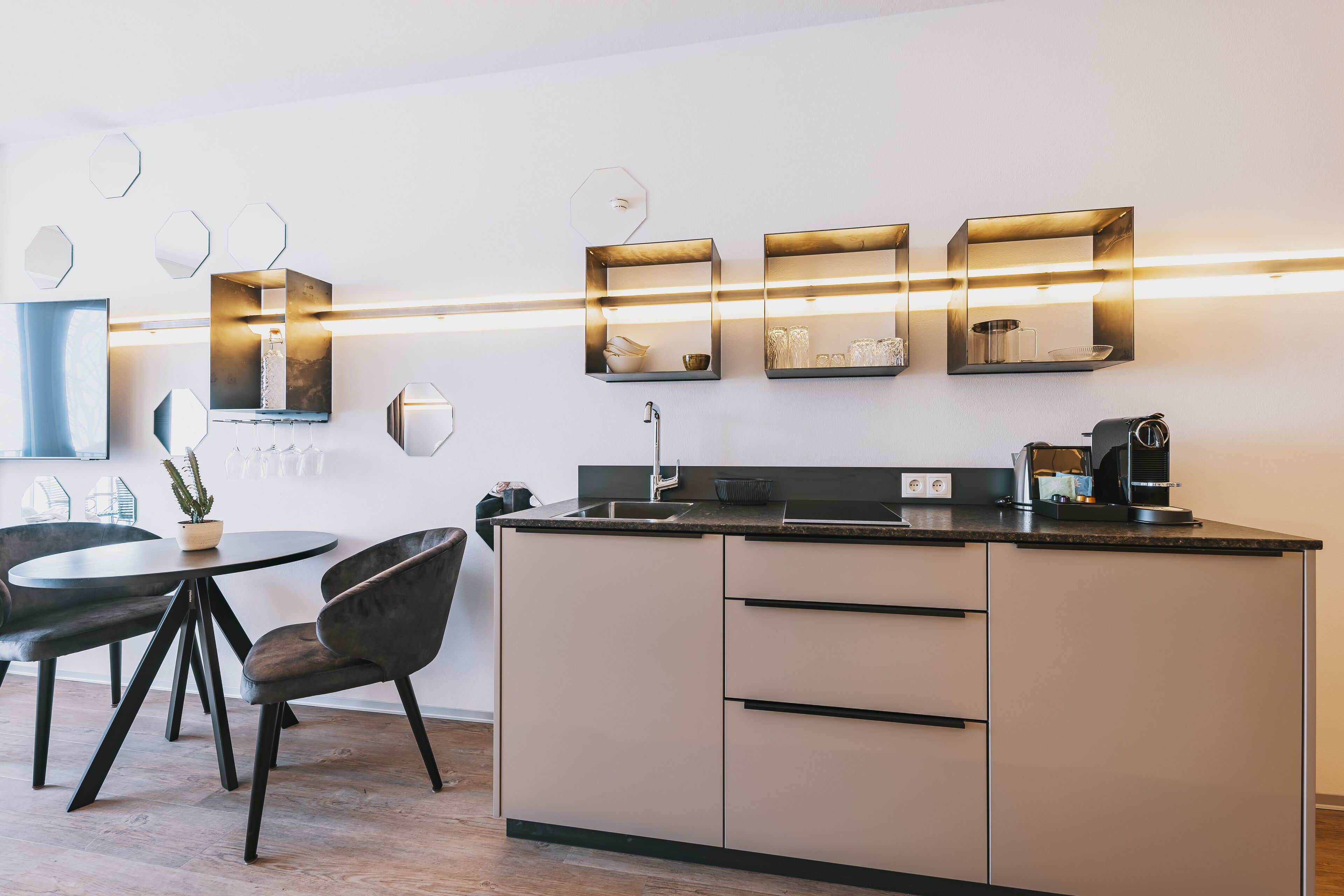 Een moderne keuken met een centraal eiland, inbouwapparatuur en hangende lampen.