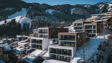 A modern hotel with multiple floors, large windows, and a view of snow-covered mountains.