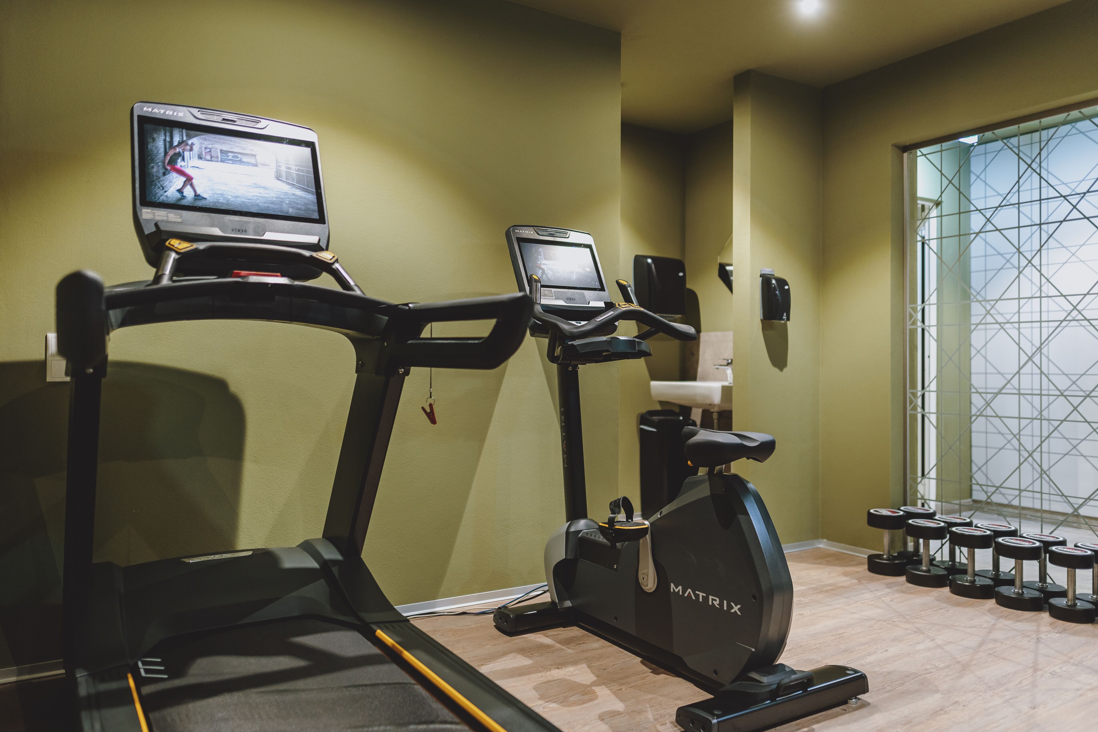 A gym with treadmills, an elliptical, and a set of dumbbells.