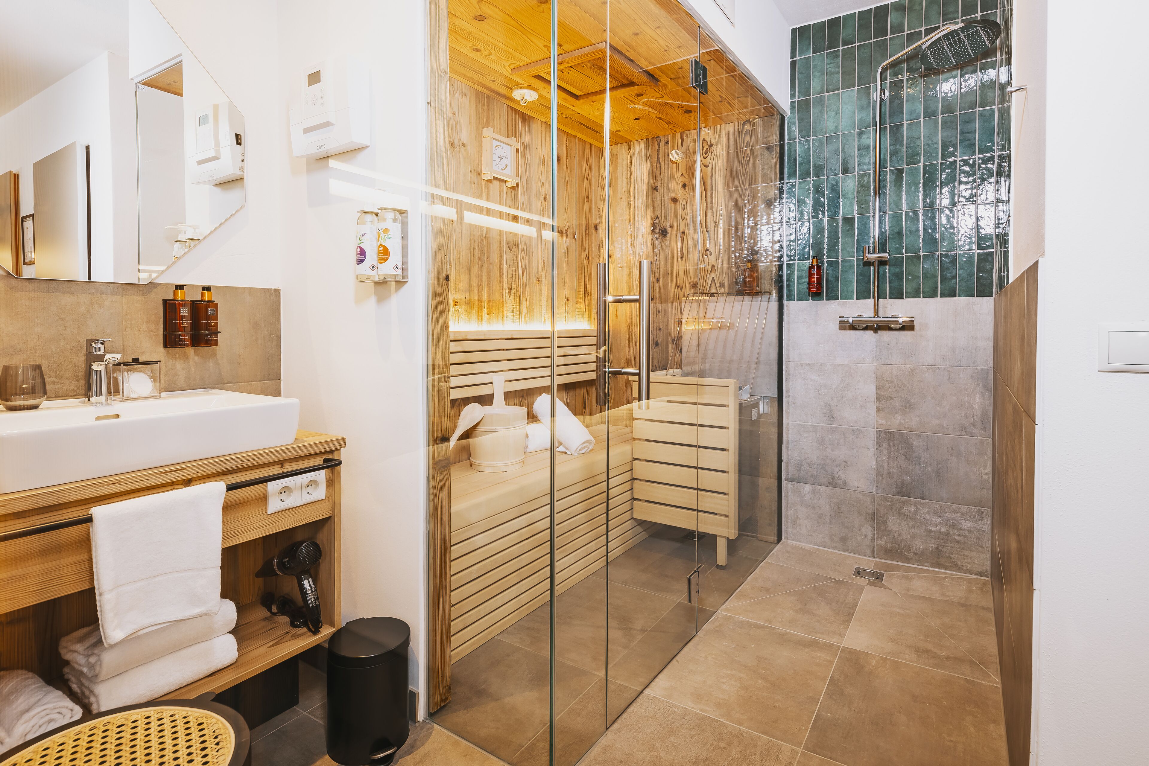 A modern bathroom with a wooden vanity, a glass shower enclosure, and a large mirror.