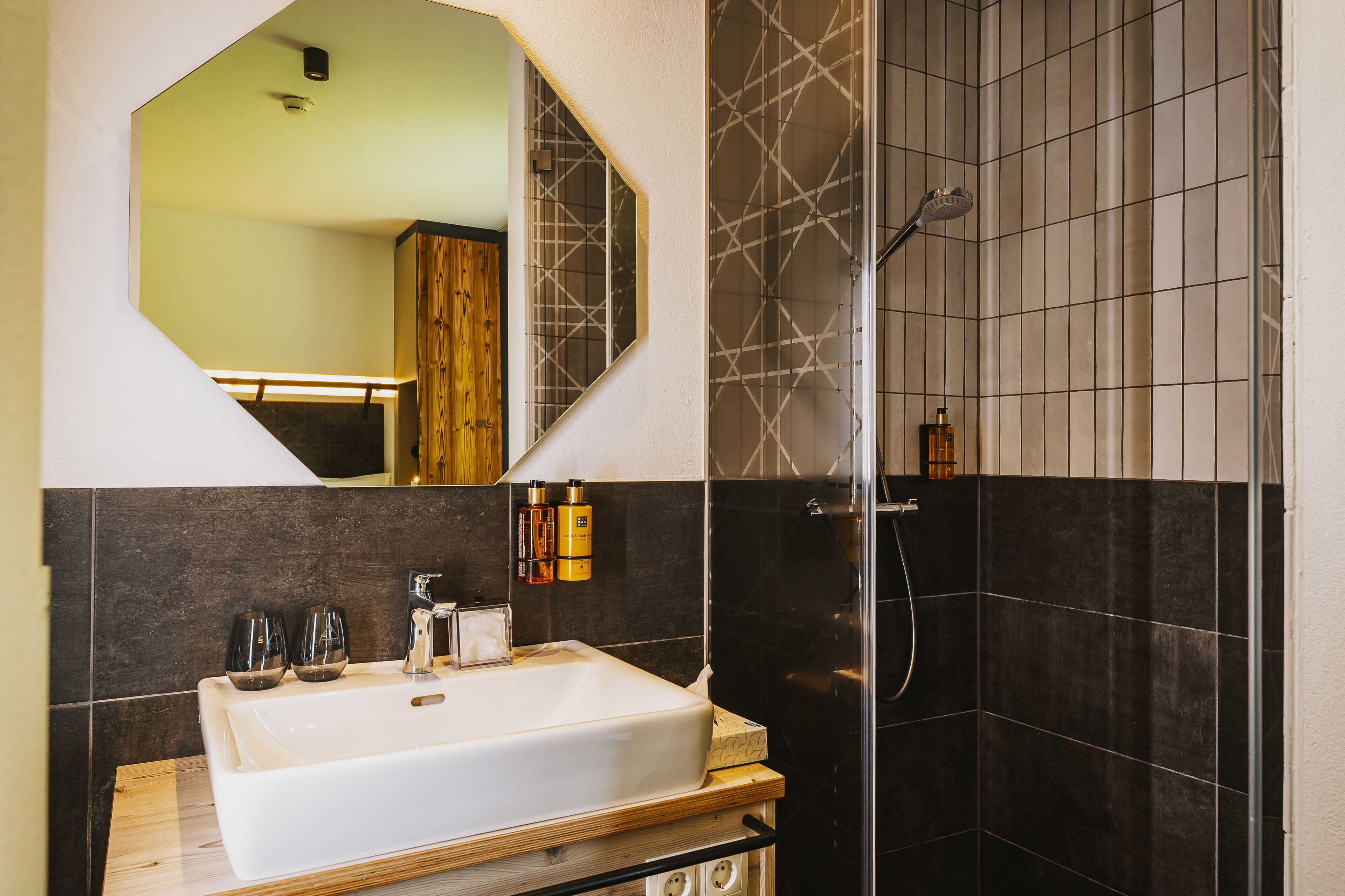 Un baño con un espejo grande, un lavabo y una ducha.