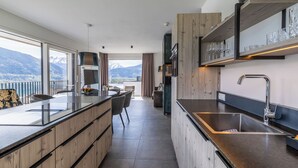 Eine moderne Küche mit einer großen Kochinsel, Holzschränken und Blick auf Berge.