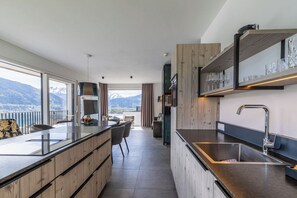 A modern kitchen with a large island, wooden cabinetry, and a view of mountains. - Nikolaus by AvenidA Zell am See (Zell am See)