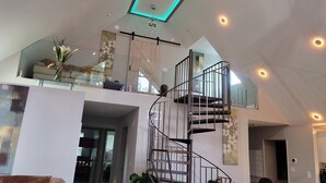 A spacious living area with a modern staircase, a glass railing, and a ceiling with recessed lighting. - Dream house with the capacity of 23 people (Fort Walton Beach)