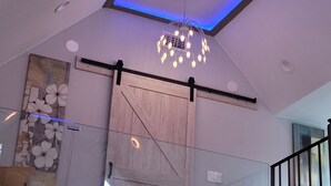 A modern interior with a glass partition, a wooden sliding door, a ceiling light fixture, and a wall-mounted light switch. - Dream house with the capacity of 23 people (Fort Walton Beach)