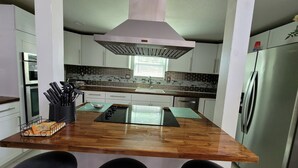 A modern kitchen with a central island, stainless steel appliances, and a backsplash with a brick pattern. - Dream house with the capacity of 23 people (Fort Walton Beach)