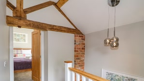 A staircase with a wooden handrail and a brick wall. - The Stables (Stoke-on-Trent)