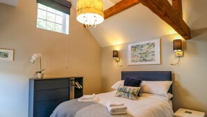 A bedroom with a bed, bedside tables, a wardrobe, a hanging plant, and artwork on the walls. - The Stables (Stoke-on-Trent)