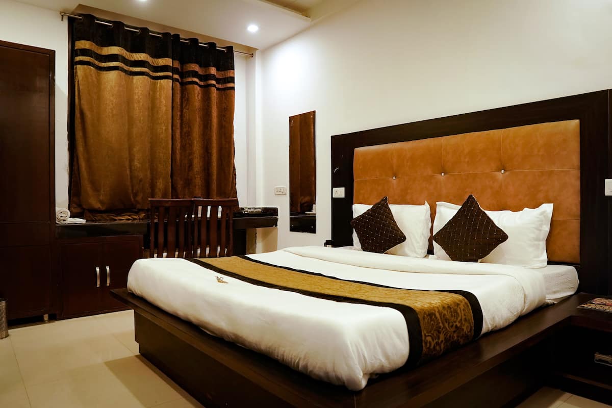 A hotel room with a large bed, a wooden desk, and a chair.