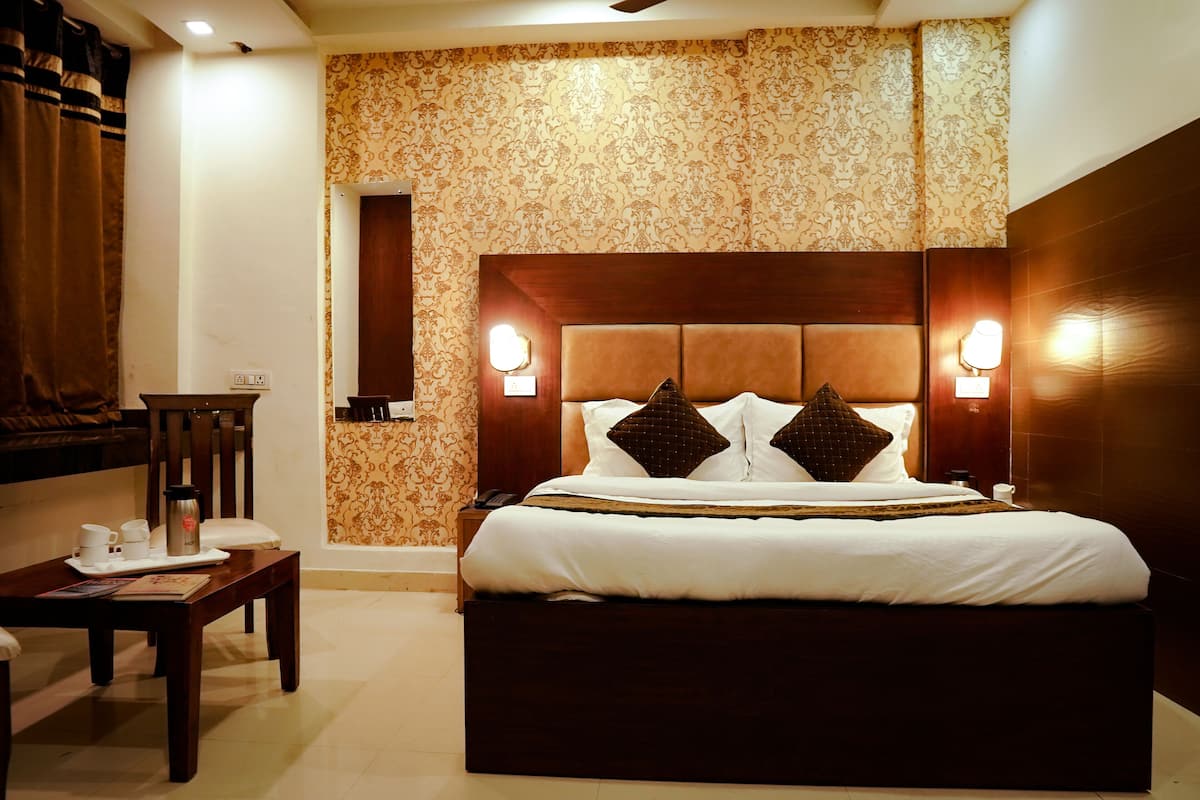 A hotel room with a large bed, two bedside tables, a chair, and a small table with a tray of items.