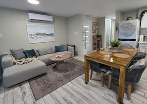 A modern living room with a sofa, coffee table, and dining table. - Guest Favorite • “True Oceanfront” Luquillo Condo • Walk to Kioskos & El Yunque (Playa Fortuna)