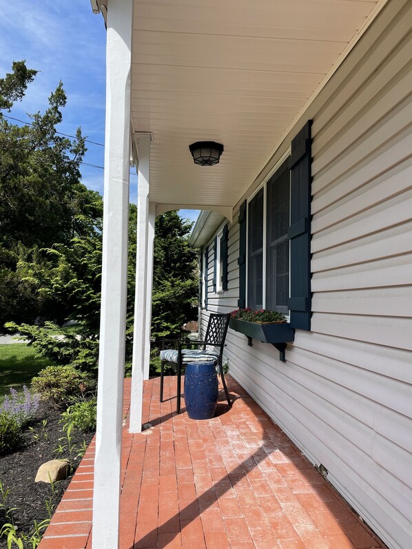 Relax on the covered porch with a comfortable chair and enjoy the serene garden surroundings.