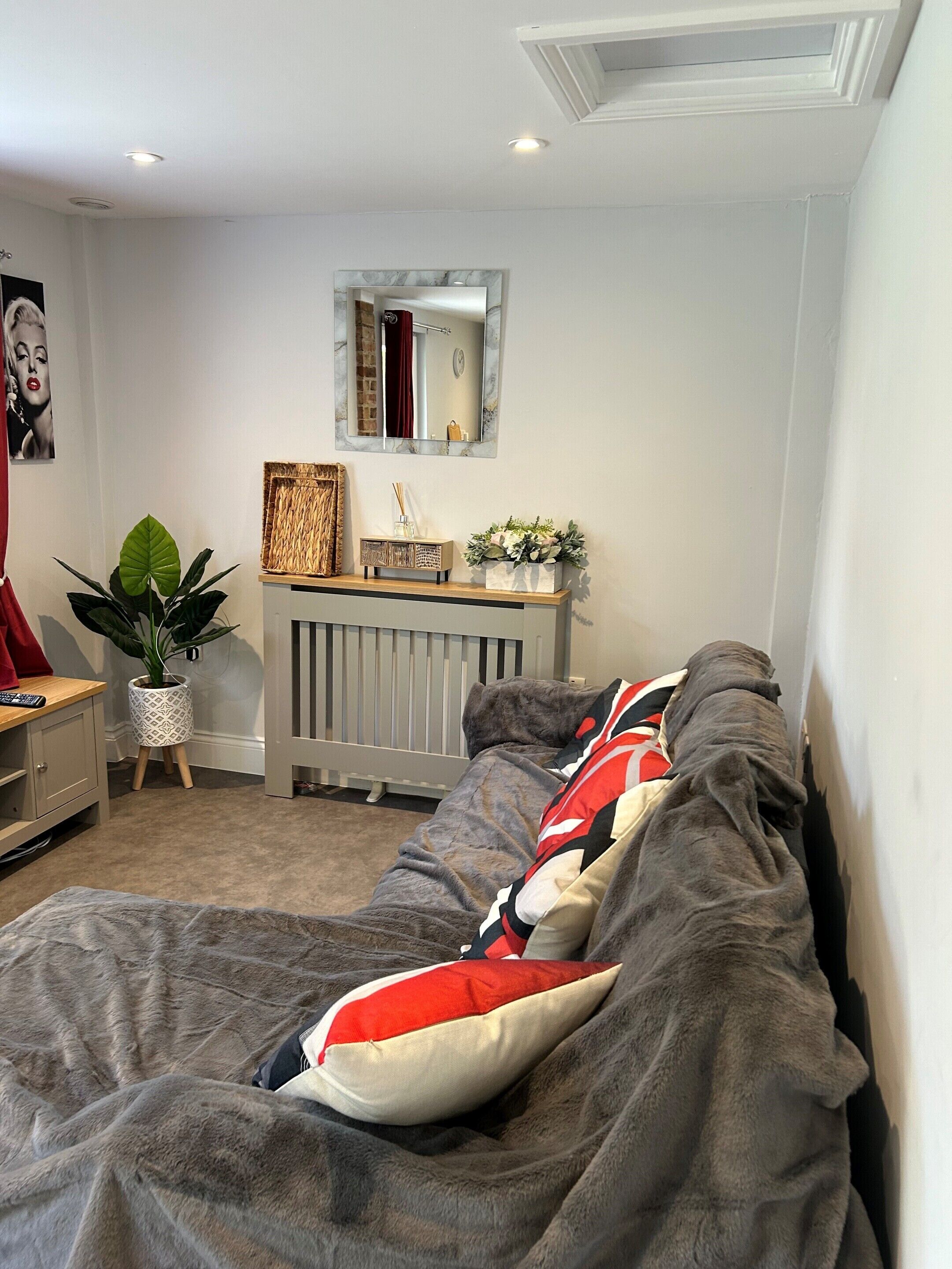 Ein gemütliches Schlafzimmer mit Bett, Nachttisch, Spiegel und Heizkörper.