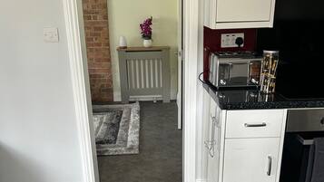 A kitchen with white cabinets, a black countertop, and a toaster. There is a brick wall and a radiator in the background.