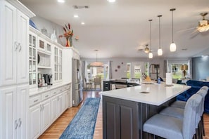 A modern kitchen with white cabinetry, a central island, and pendant lighting. - The Bayou House - Lakefront, Boat Dock, Views! (Hot Springs)