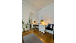 Una sala de estar moderna con piso de madera, un tapete gris, un sofá blanco, una silla negra y un espejo grande en la pared.