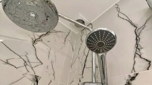 Esquina de un baño con cabezal de ducha y una manguera de ducha.