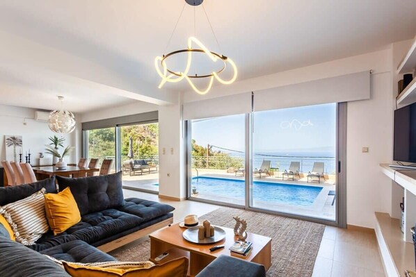 A modern living room with a sofa, coffee table, and a view of an outdoor swimming pool.