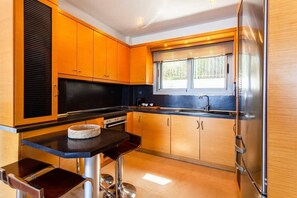 Une cuisine moderne avec des meubles en bois, un plan de travail noir et un réfrigérateur en acier inoxydable.