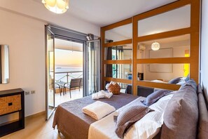 Een moderne hotelkamer met een groot bed, een balkon met uitzicht en een schuifdeur naar een buitenruimte.