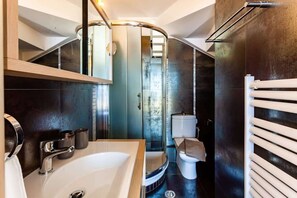 Een moderne badkamer met een gebogen spiegel, een wit wastafel, een toilet en een handdoekhouder.