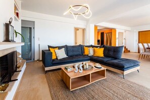 Een moderne woonkamer met een hoekbank, een salontafel en een open haard.