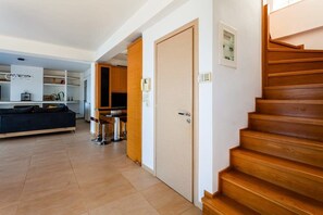 A modern interior with a wooden staircase, a kitchen area, and a seating area with a sofa and coffee table. - Aigli Luxury Villa - Panoramic Seaview Retreat (Kalamata)