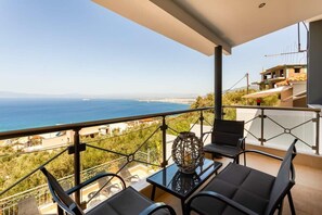 A balcony with a view of the sea, a table with chairs, and a decorative item.