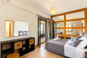 Une chambre moderne avec un lit, des tables de chevet, un miroir et une porte-fenêtre coulissante donnant sur un balcon.